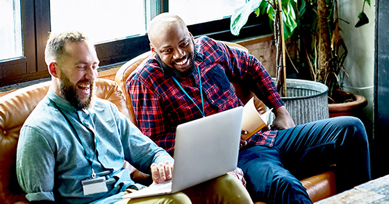Two office workers viewing something on a laptop