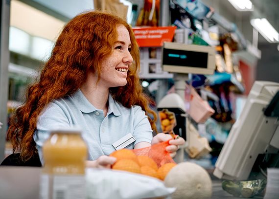 Young female checkout staff in a supermarket.